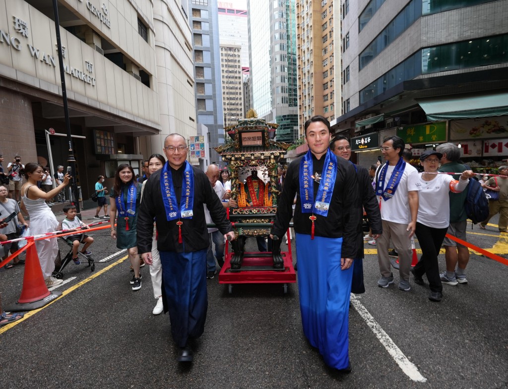 圖三為東華三院主席何猷啟先生（前排右）聯同董事局成員隨文武二帝鑾輿出巡，吸引途人駐足觀賞。