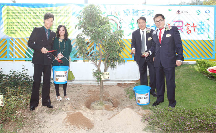 東華三院董事局成員為樹苗灑上由廚餘機製成的有機肥料。