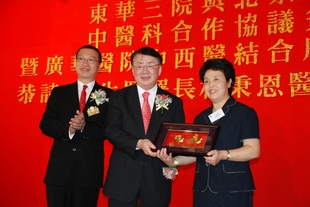 衞生署署長林秉恩醫生太平紳士(中)致送紀念品予梁曉春教授(右)，由東華三院主席張佐華陪同。