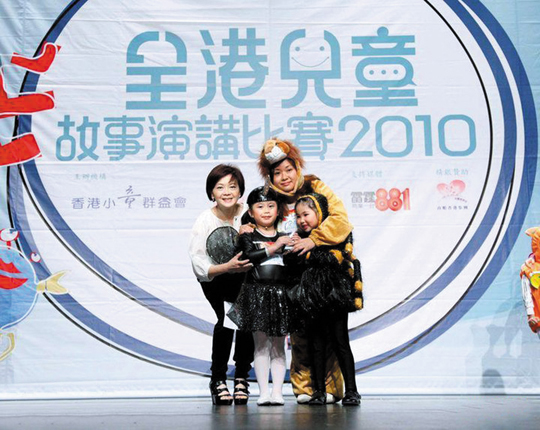 東華三院黎鄧潤球幼稚園的鍾老師 （後排右）扮演雄糾糾的獅子大王，兩位高班的小朋友張銳婷（前排左）及林珮盈（前排右）則扮演蚊子和蜘蛛，生動地說出教人不要驕傲的故事。她們造型可愛、扮相維肖維妙，引得觀眾捧腹大笑，最後勇奪「師生合作組」冠軍。鍾老師和兩位學生於賽後與評判查小欣小姐合照。