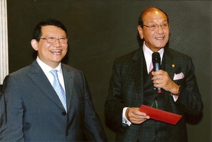 邁拿鐘錶國際有限公司董事長周錦光先生（左）樂善好施，將其六秩榮壽的賀禮共港幣十萬元交由東華三院1966/1967年度主席孫秉樞博士MBE太平紳士（右）轉贈本院支持社會服務，讓有需要的家庭受惠。