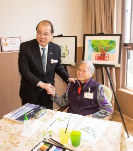 綜合中心94歲高齡的院友黃玉少婆婆(右)向政務司司長張建宗GBS太平紳士(左)介紹其畫作。